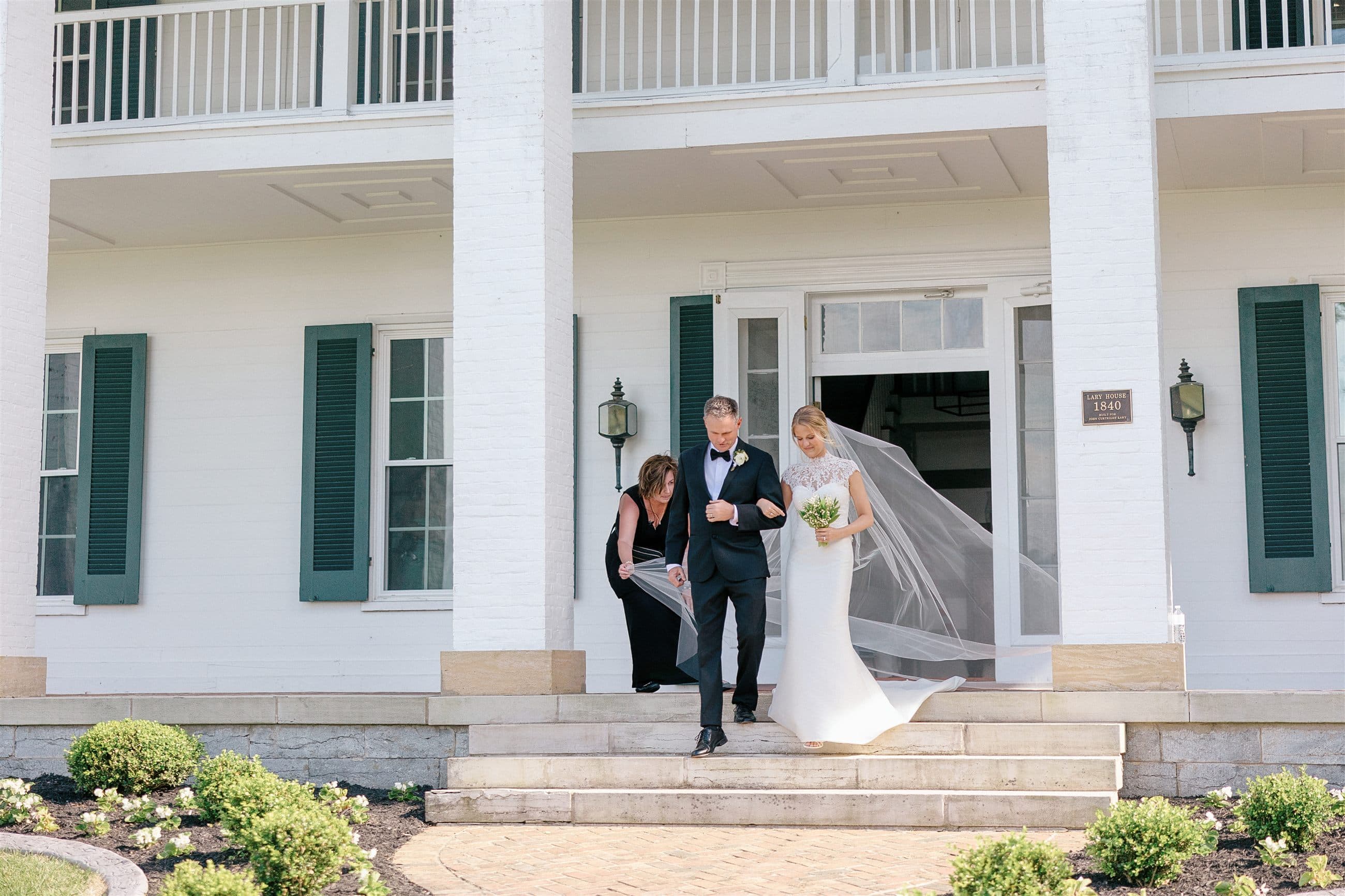 A bride and her father stepping out the manor doors