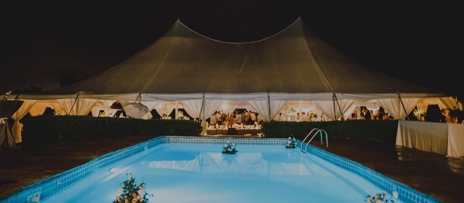The sailcloth tent glowing over the pool after dark